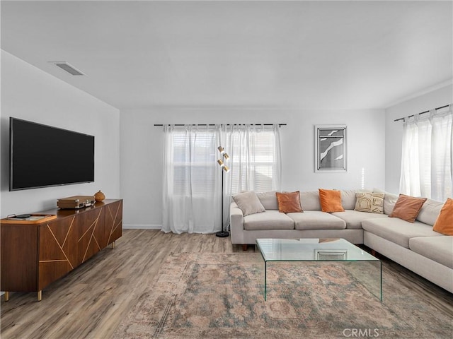 living area featuring visible vents, plenty of natural light, and wood finished floors