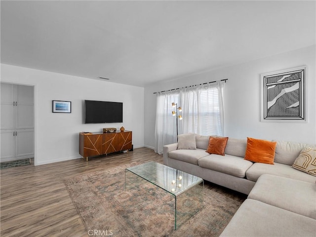 living area with wood finished floors, visible vents, and baseboards