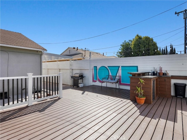 wooden terrace with area for grilling and a fenced backyard