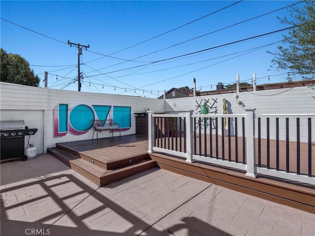 wooden deck featuring a patio area, area for grilling, and a fenced backyard