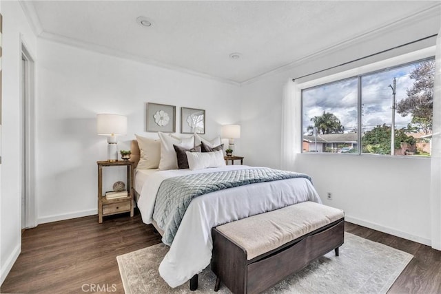 bedroom featuring baseboards, wood finished floors, and crown molding