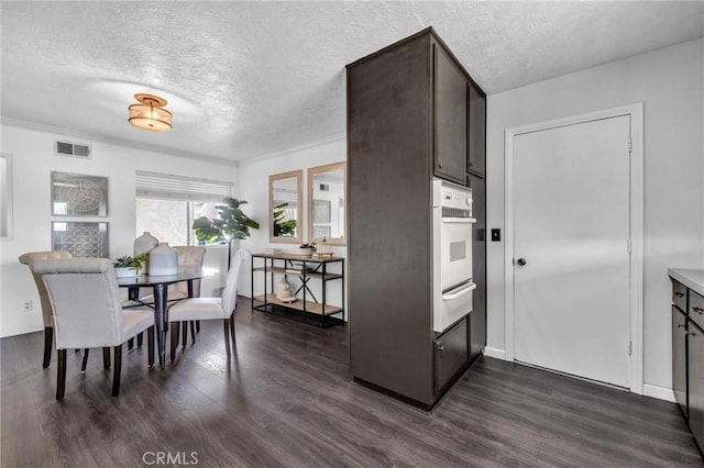 dining area featuring baseboards, visible vents, dark wood-style flooring, and a textured ceiling