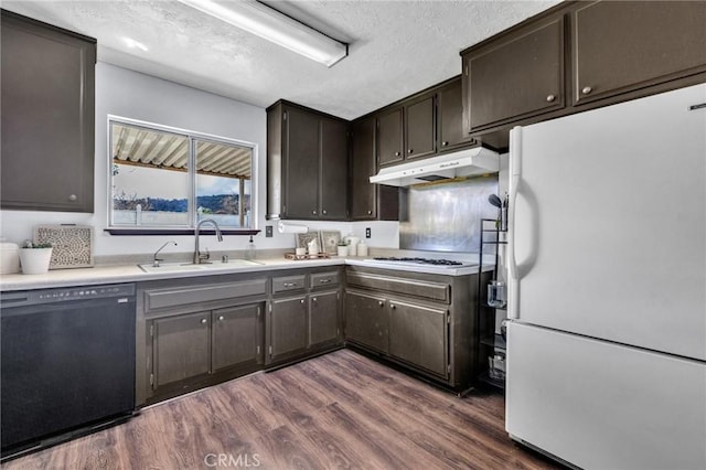 kitchen with white appliances, dark wood-style floors, a sink, under cabinet range hood, and a textured ceiling