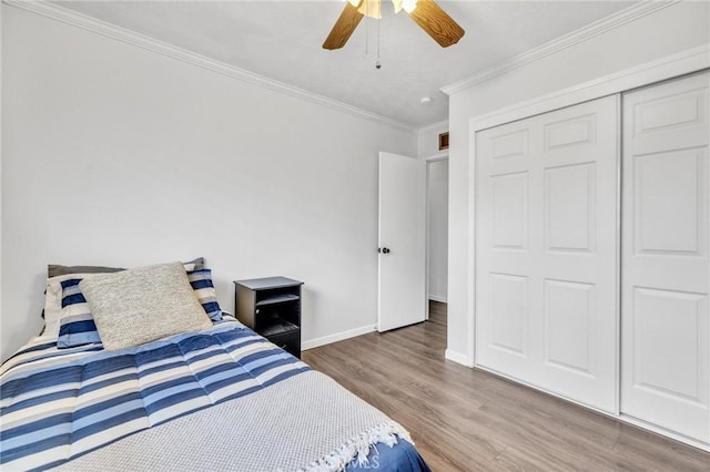 bedroom featuring ornamental molding, wood finished floors, a closet, baseboards, and ceiling fan