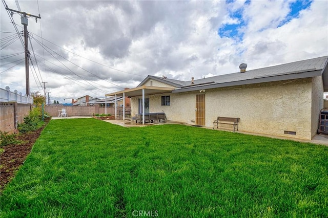 back of house with crawl space, stucco siding, a lawn, a fenced backyard, and a patio area