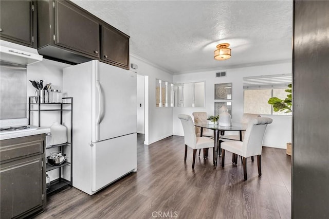 kitchen with visible vents, dark wood-style flooring, freestanding refrigerator, under cabinet range hood, and a textured ceiling