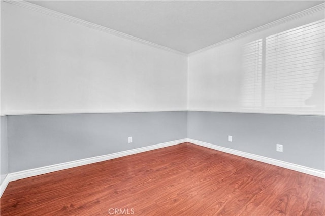 spare room with wood finished floors, baseboards, and ornamental molding