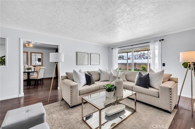 living room featuring ornamental molding, a textured ceiling, baseboards, and wood finished floors