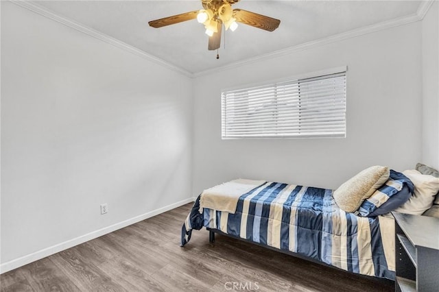 bedroom featuring a ceiling fan, crown molding, baseboards, and wood finished floors