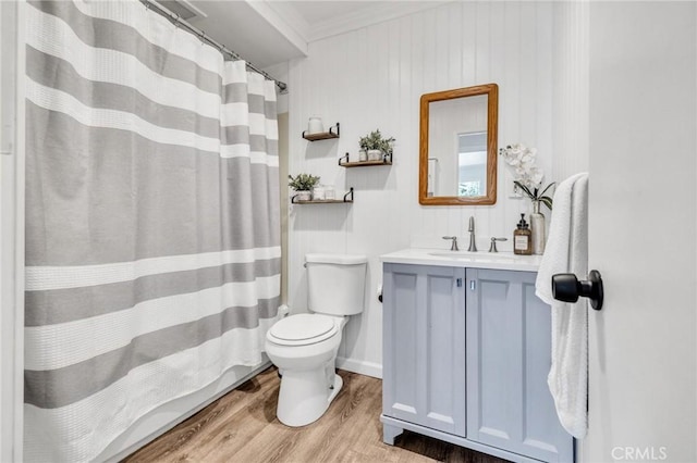 bathroom featuring vanity, a shower with shower curtain, wood finished floors, ornamental molding, and toilet