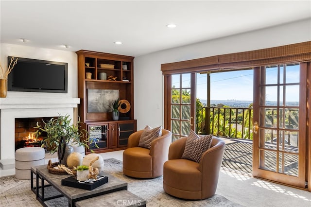 living room featuring recessed lighting, a lit fireplace, and carpet flooring