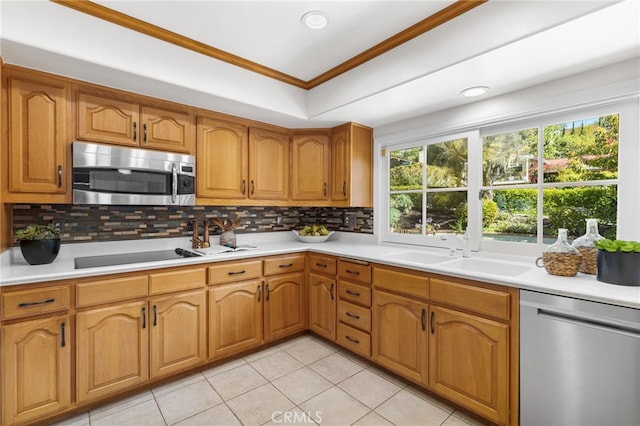 kitchen with a sink, light countertops, ornamental molding, and stainless steel appliances