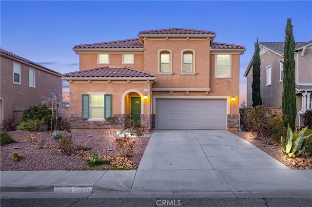 mediterranean / spanish-style house featuring stucco siding, concrete driveway, an attached garage, and a tiled roof