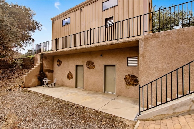 back of house featuring a patio area, stucco siding, and stairs