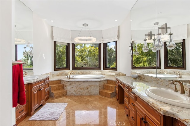 bathroom featuring a garden tub, two vanities, and a sink