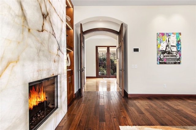 hall with arched walkways, french doors, dark wood-type flooring, and baseboards