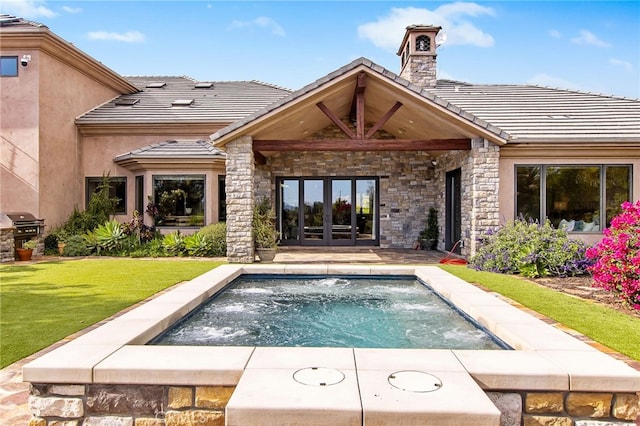 view of pool with grilling area, french doors, and a yard