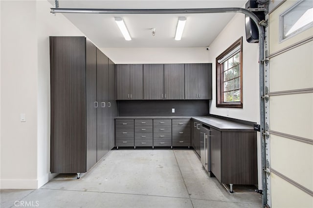 kitchen featuring dark brown cabinets, baseboards, dark countertops, and concrete flooring