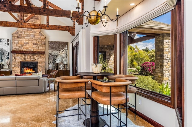 dining space with baseboards, high vaulted ceiling, a stone fireplace, beamed ceiling, and a chandelier