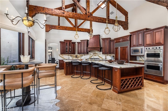 3221 Integrity Way, Fallbrook, CA 92028 - kitchen featuring built in appliances, custom exhaust hood, high vaulted ceiling, arched walkways, and a large island with sink