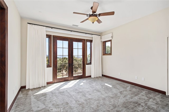 carpeted spare room featuring visible vents, french doors, baseboards, and a ceiling fan