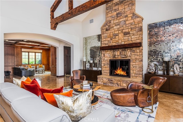 living area with visible vents, beamed ceiling, a fireplace, arched walkways, and high vaulted ceiling