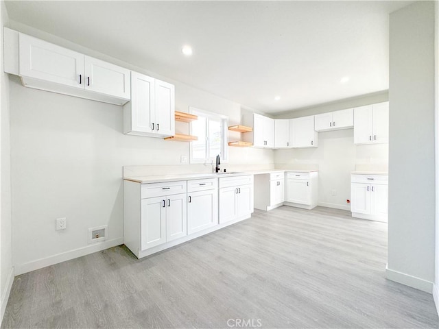 kitchen featuring open shelves, light wood-type flooring, baseboards, and white cabinets