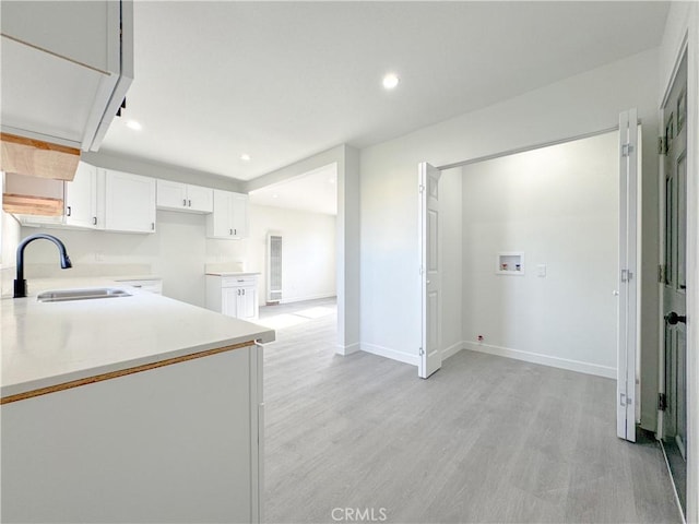 kitchen with white cabinets, light countertops, light wood-style floors, and a sink