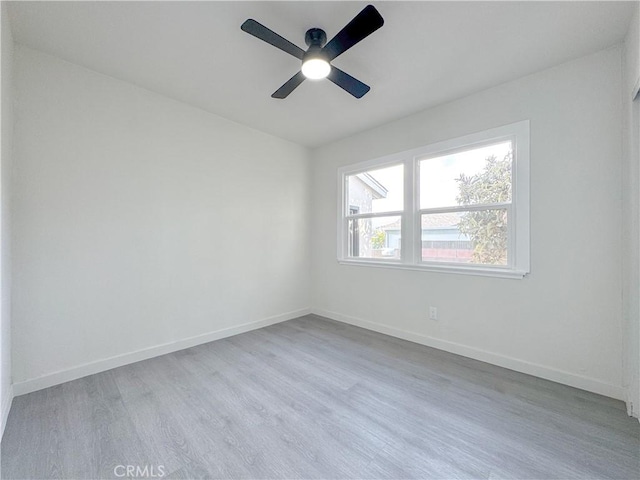 empty room with wood finished floors, a ceiling fan, and baseboards