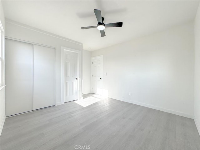 unfurnished bedroom with a closet, baseboards, wood finished floors, and a ceiling fan