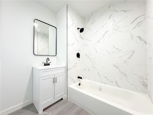 bathroom featuring tub / shower combination, baseboards, wood finished floors, and vanity