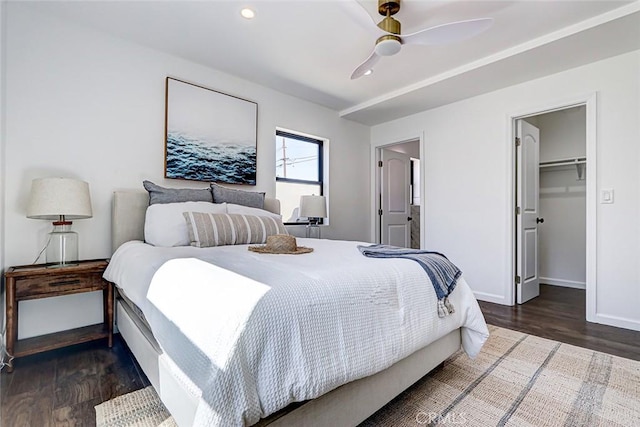 bedroom with wood finished floors, baseboards, recessed lighting, ceiling fan, and a walk in closet