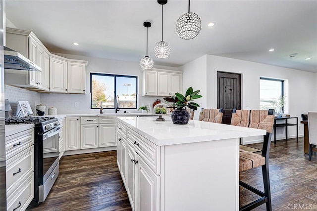 kitchen with gas stove, dark wood-style flooring, light countertops, a kitchen breakfast bar, and a center island