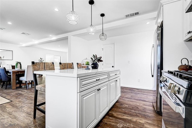 kitchen with dark wood-type flooring, a kitchen breakfast bar, visible vents, and appliances with stainless steel finishes