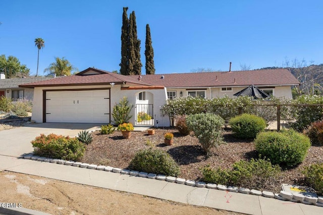 single story home with stucco siding, a garage, driveway, and fence