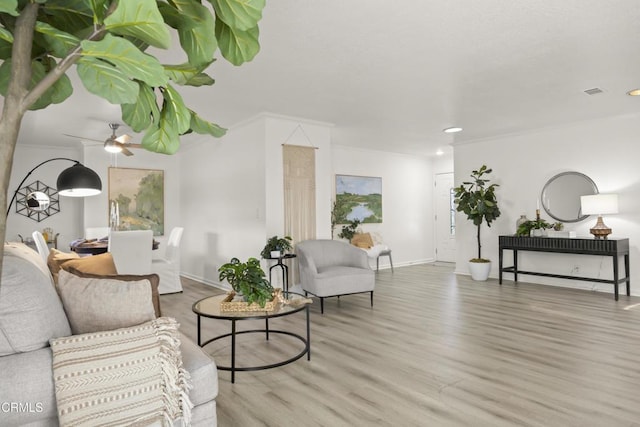 living room with baseboards, crown molding, a ceiling fan, and wood finished floors