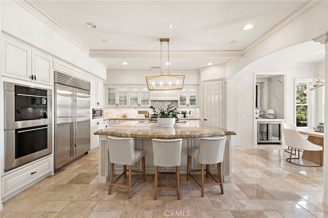 10 Corte Vizcaya, San Clemente, CA 92673 - kitchen with built in appliances, a center island, decorative backsplash, light stone countertops, and a breakfast bar