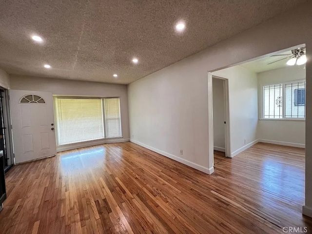 empty room featuring a ceiling fan, a textured ceiling, wood finished floors, recessed lighting, and baseboards