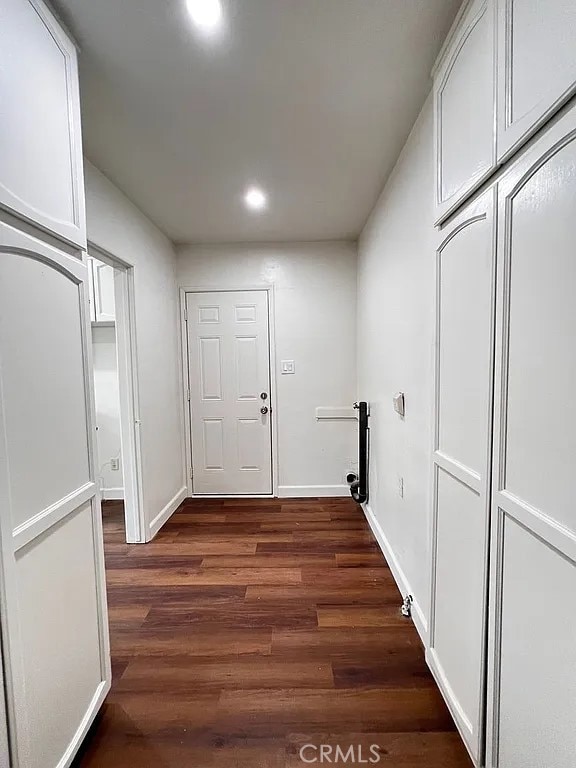 corridor featuring dark wood-style floors, recessed lighting, and baseboards