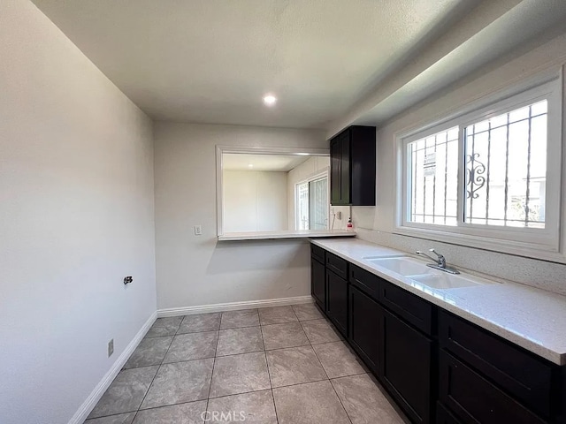 kitchen with a sink, dark cabinetry, and light countertops