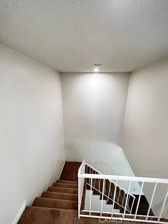 stairs featuring a textured ceiling