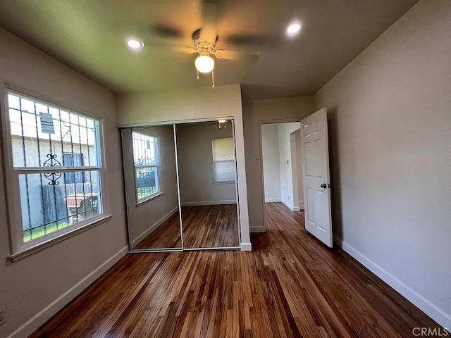 unfurnished bedroom with a closet, baseboards, dark wood-style floors, and a ceiling fan