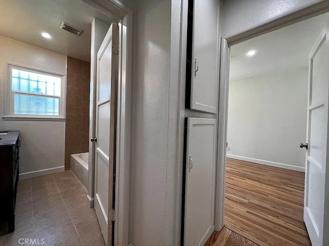 hallway with recessed lighting, visible vents, baseboards, and wood finished floors