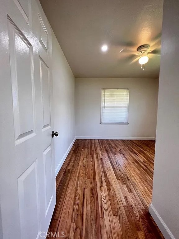 spare room with a ceiling fan, dark wood-style floors, and baseboards