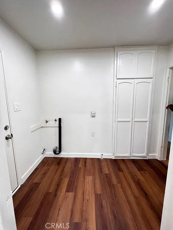 laundry area with hookup for a washing machine, cabinet space, dark wood-style flooring, and baseboards