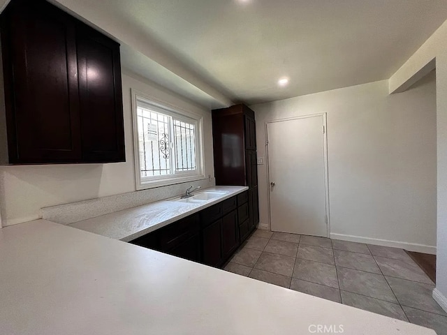 kitchen featuring light tile patterned flooring, light countertops, baseboards, and a sink