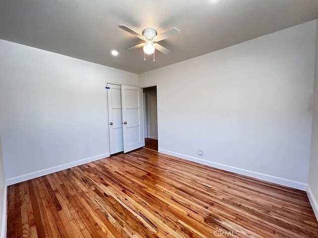 unfurnished bedroom featuring a closet, baseboards, wood finished floors, and a ceiling fan