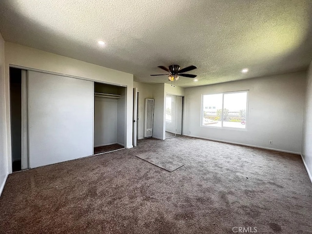 unfurnished bedroom with ceiling fan, carpet, two closets, and a textured ceiling