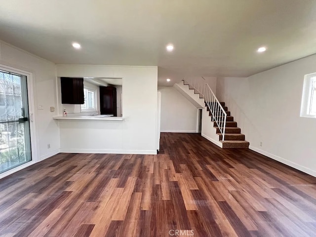 unfurnished living room with dark wood-type flooring, stairway, and recessed lighting