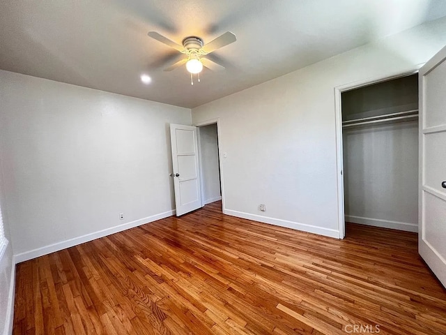 unfurnished bedroom with a closet, a ceiling fan, baseboards, and wood finished floors